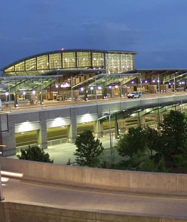 A view of the domed glass walls of the T.F. Green Airport from a distance. Concrete pillars and roads in front.